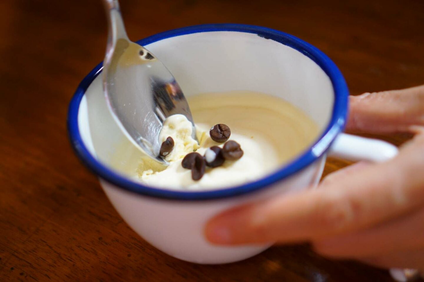 tazza bianca con bordo blu con dentro crema e chicchi di caffè