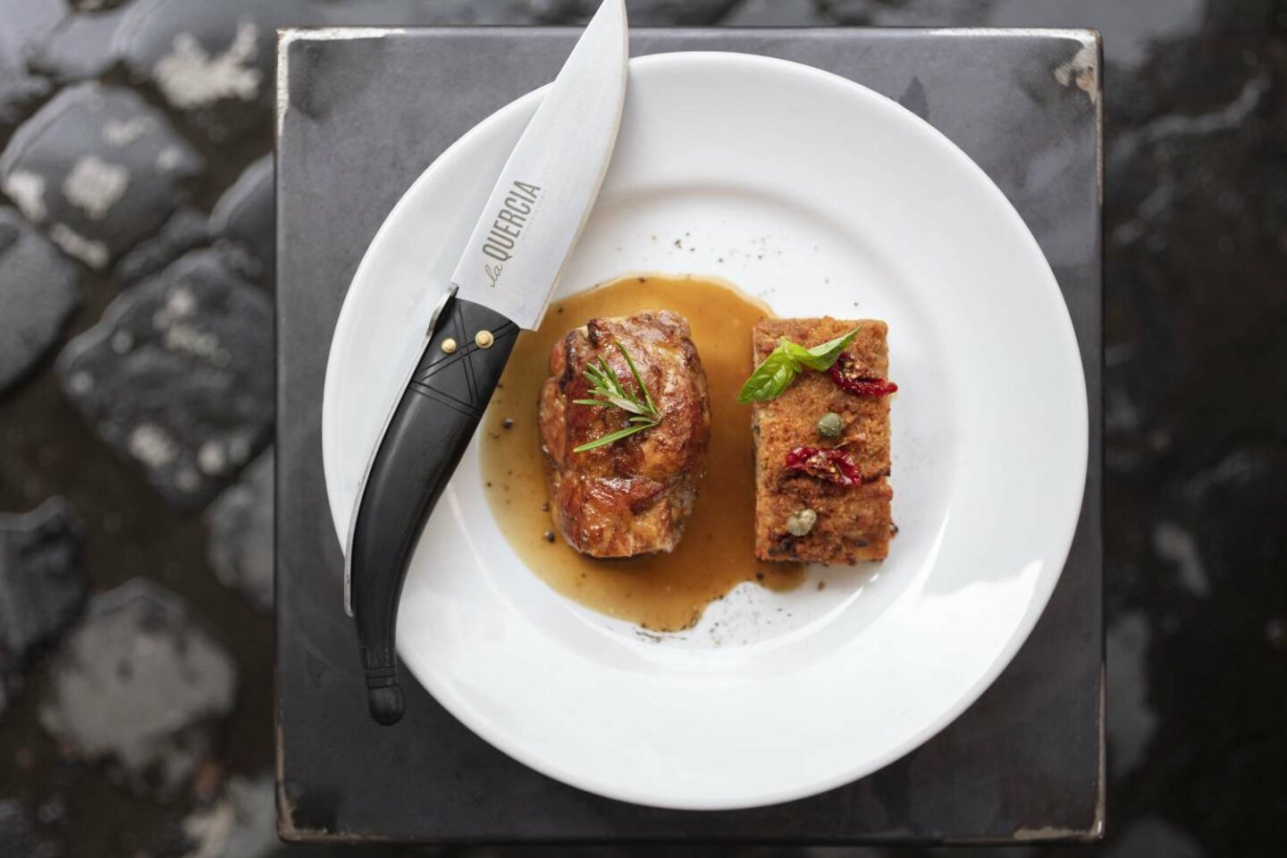 piatto bianco con due filetti di carne e coltello con logo la quercia